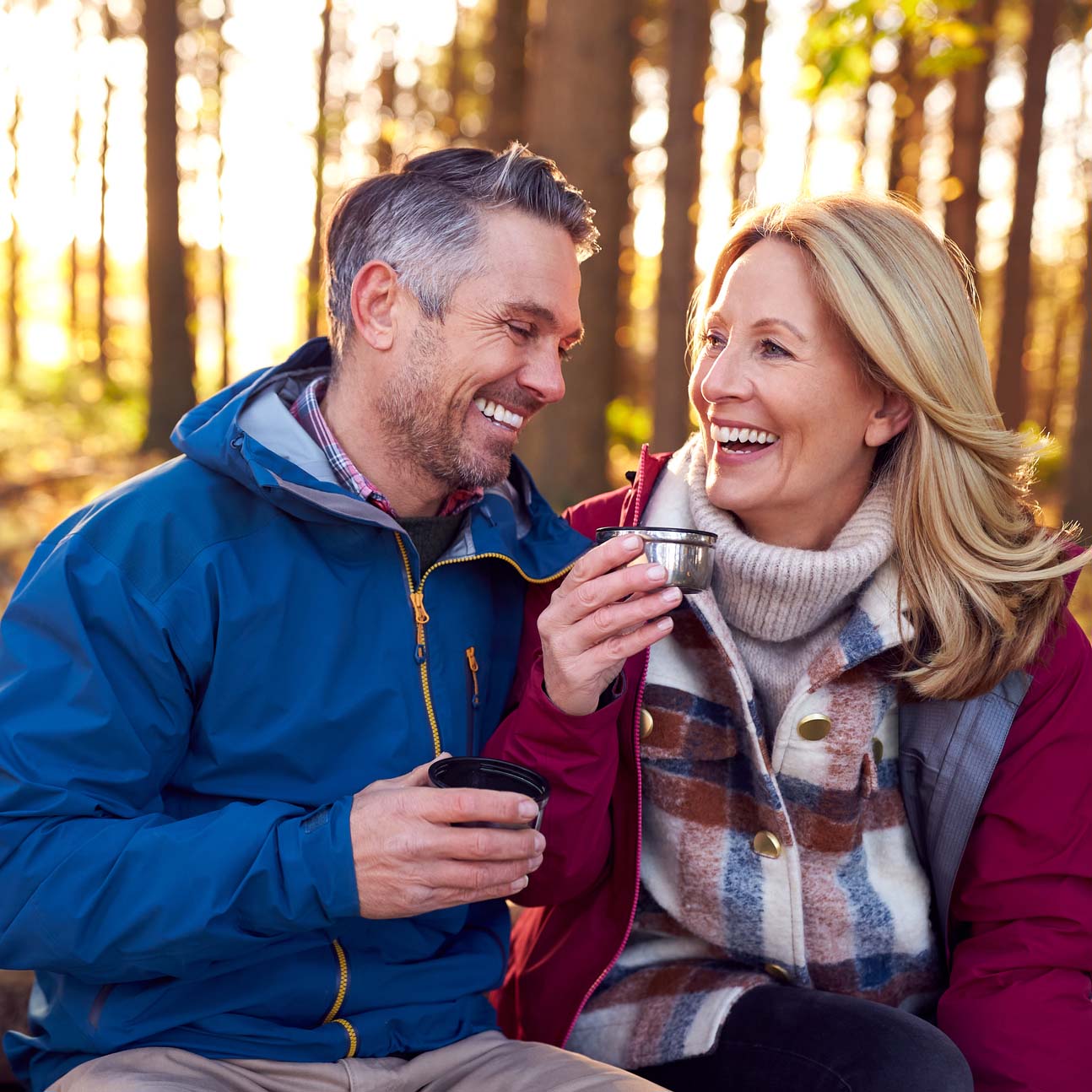Couple outdoors drinking hot beverages and smiling