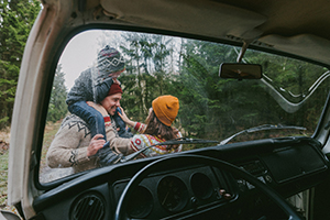 family out on hike viewed through windshield of their camper van